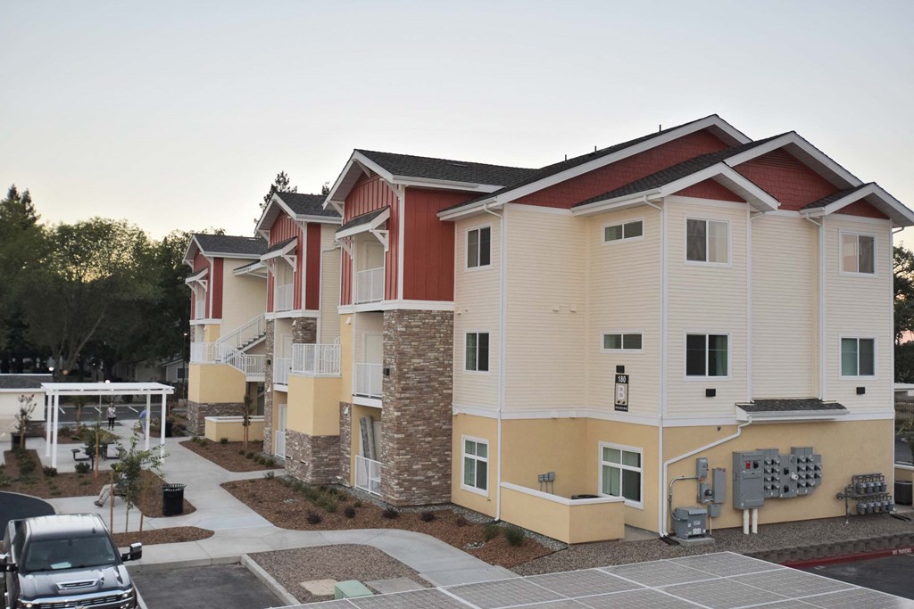 a row of apartments with cars parked in a parking lot