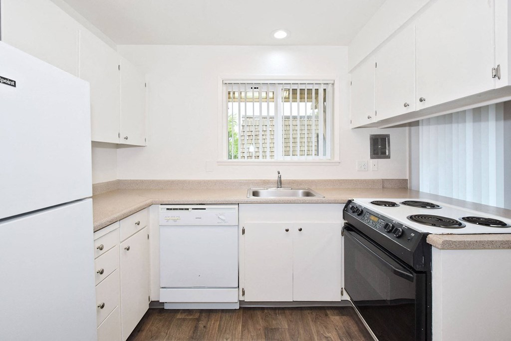 a kitchen with white cabinets and appliances and a window