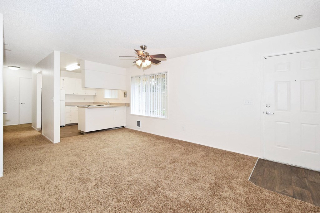 an empty living room and kitchen with a ceiling fan