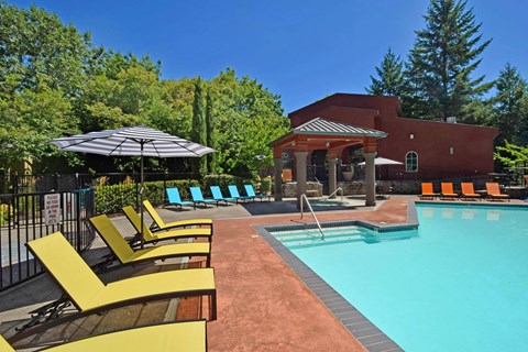 A pool area with a red building and yellow sun loungers.
