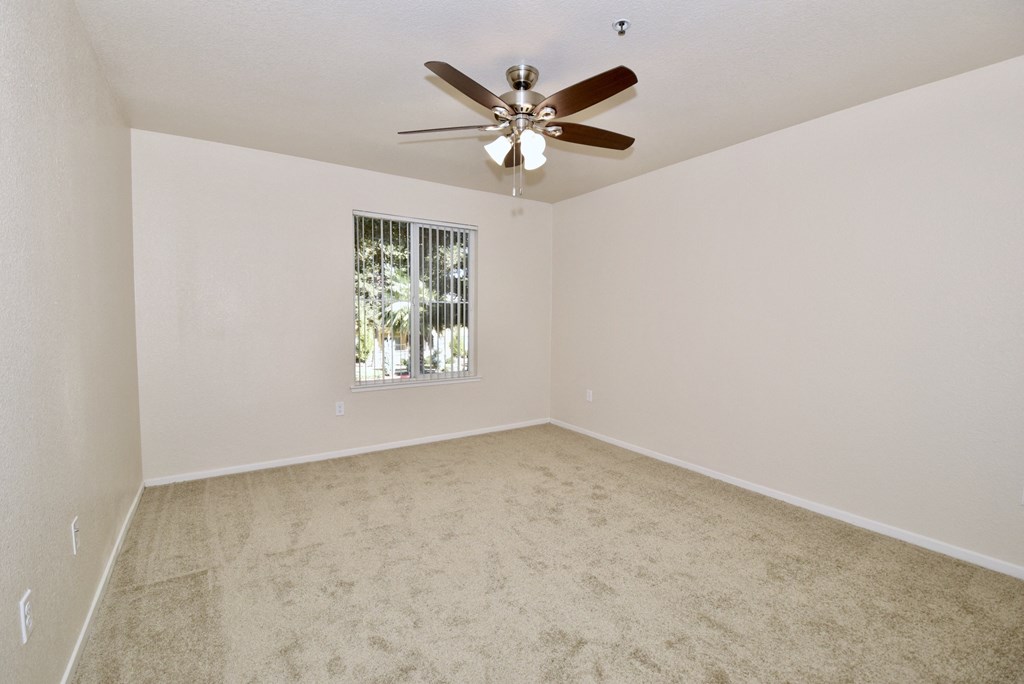 an empty living room with a ceiling fan and a window