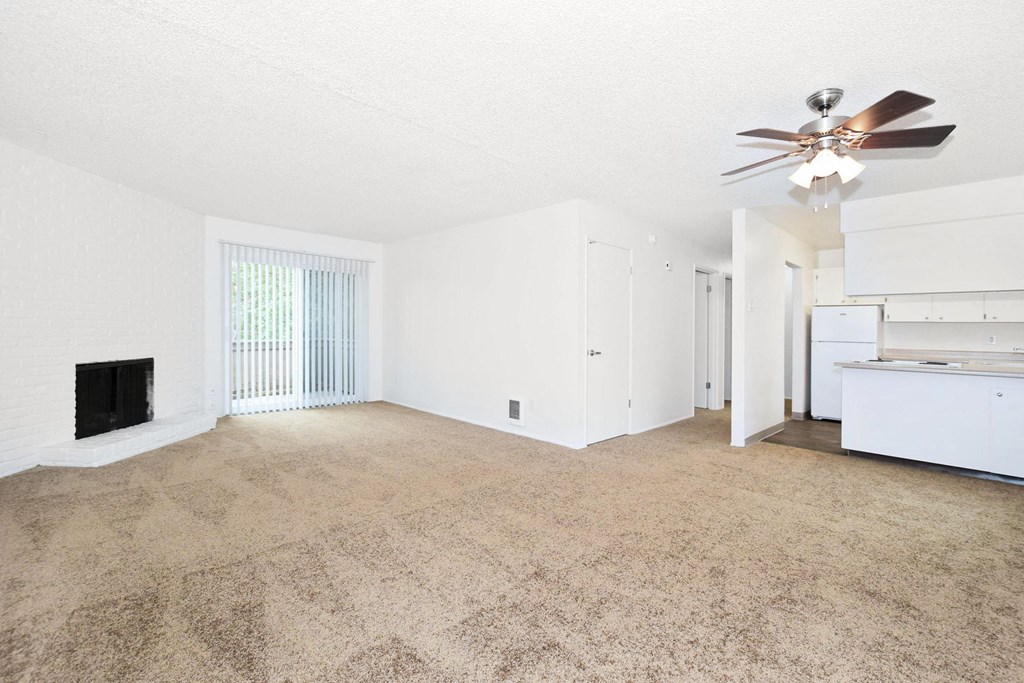 an empty living room with a ceiling fan and a window