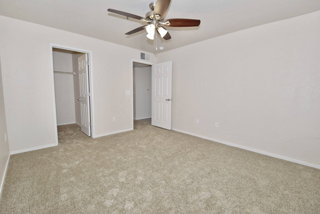 an empty living room with a ceiling fan and a closet