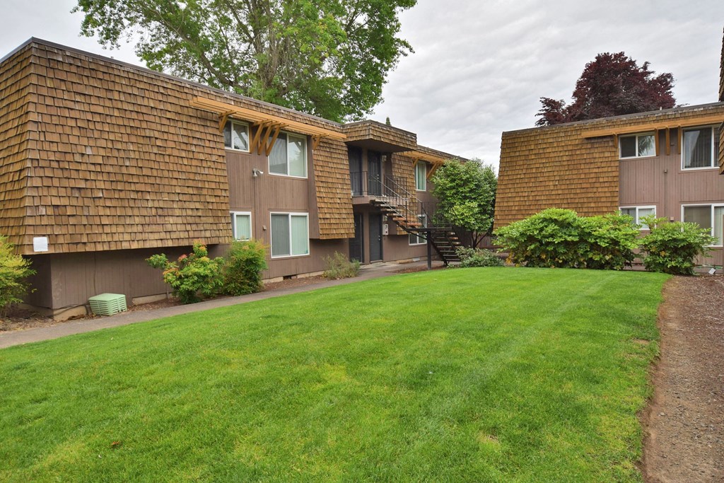 a view of two apartment buildings with a green lawn