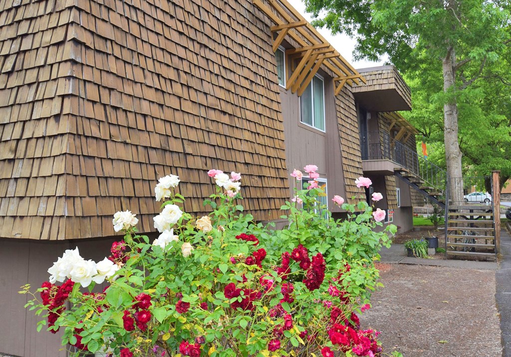 the outside of a cabin with flowers in front of it