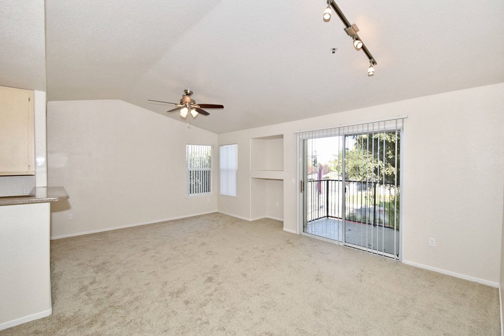 an empty living room with a sliding glass door to a balcony