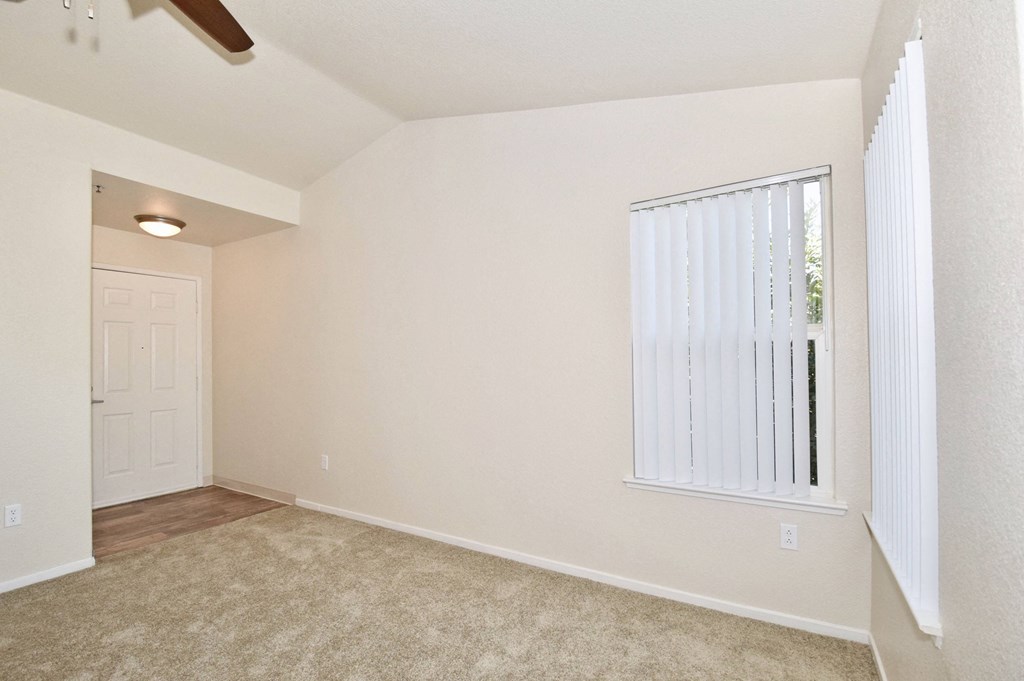 an empty living room with a window and a white door