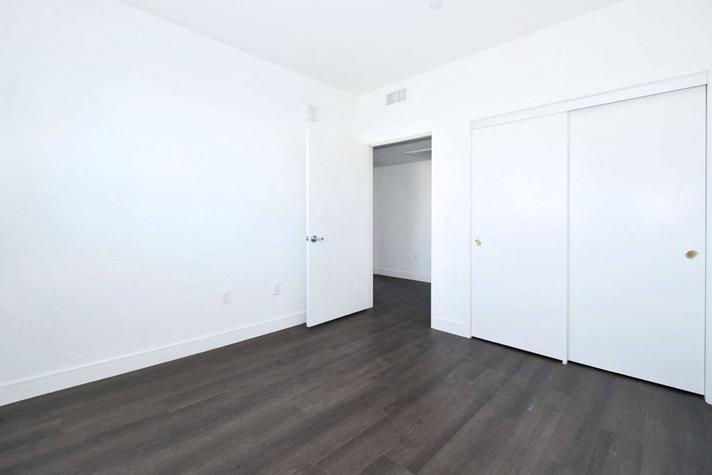 an empty room with white walls and wood floors