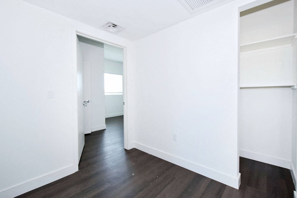 an empty room with white walls and wood floors