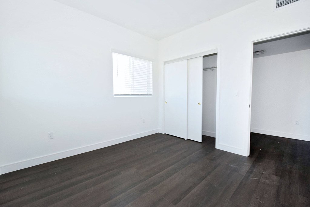 an empty room with white walls and wood floors and a closet