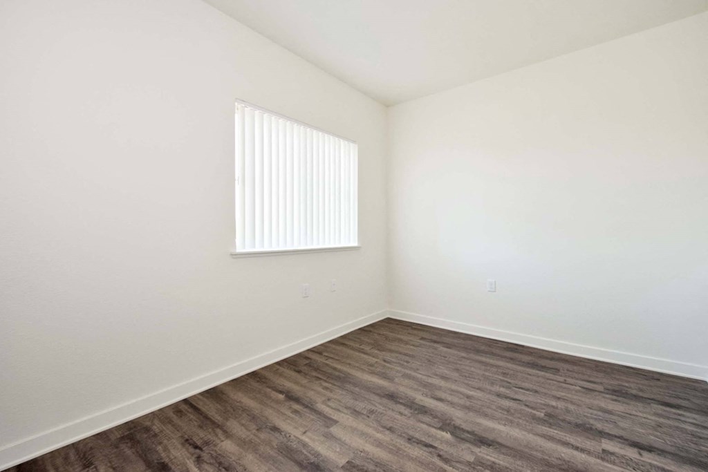 one of the bedrooms with hardwood floors and a window