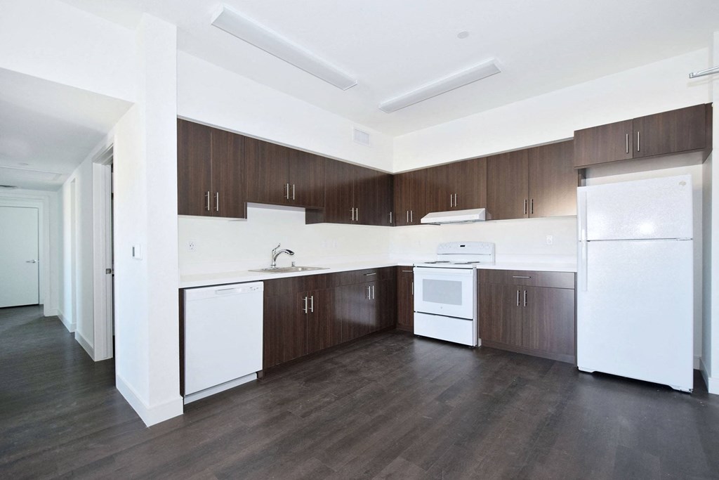 an empty kitchen with white appliances and wooden cabinets