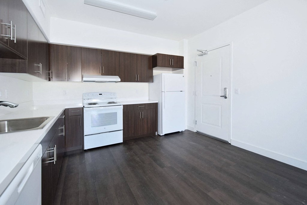 an empty kitchen with white appliances and wooden cabinets