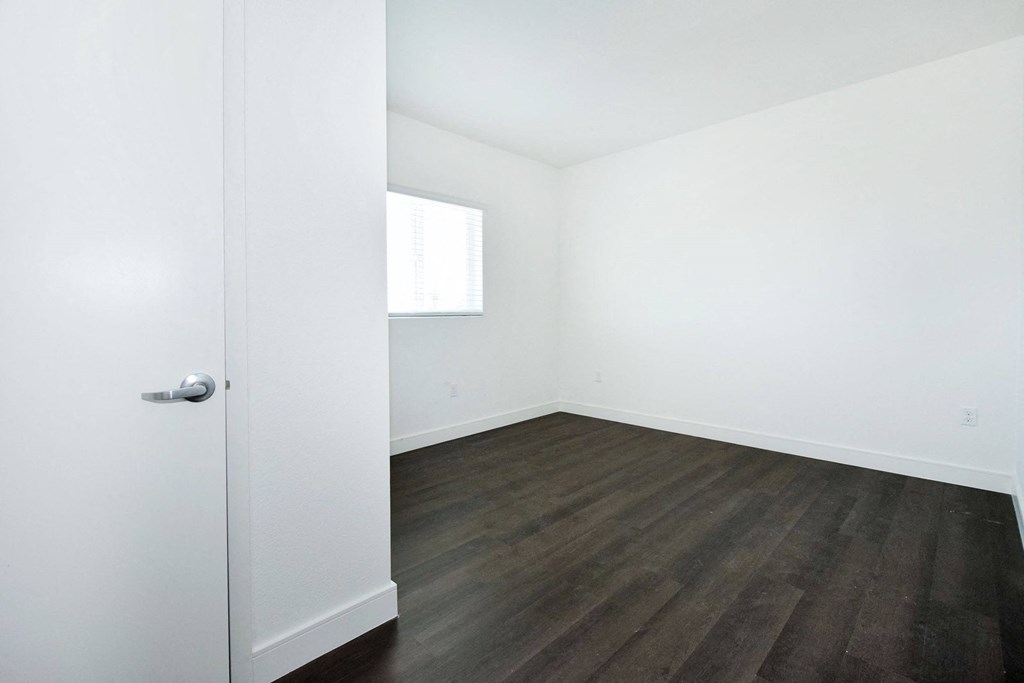 an empty room with white walls and wood floors