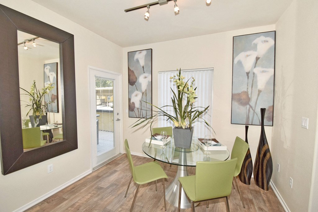 a dining room with a glass table and green chairs