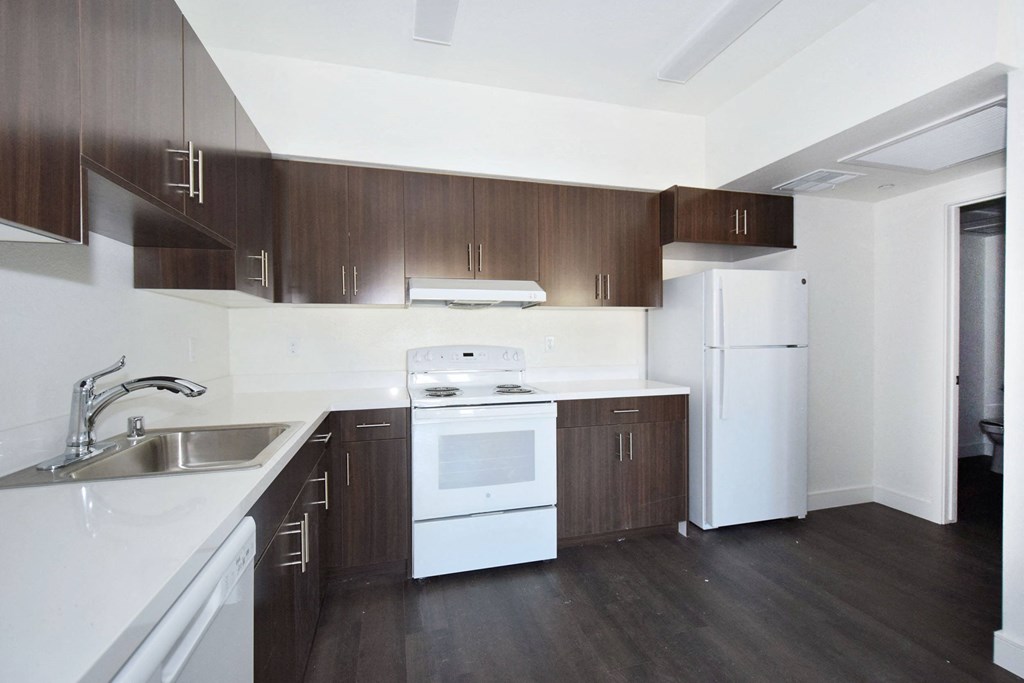 an empty kitchen with white appliances and wooden cabinets