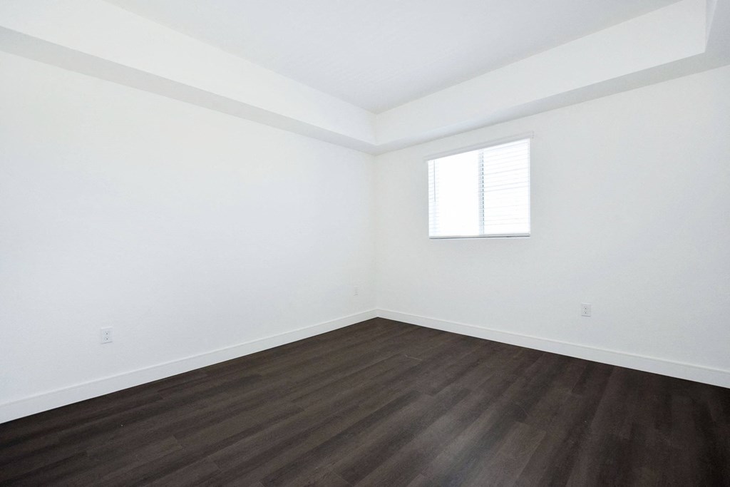 an empty room with white walls and wooden floors and a window