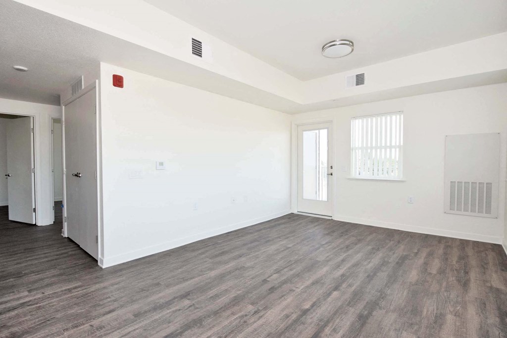 the living room of an apartment with white walls and hardwood floors