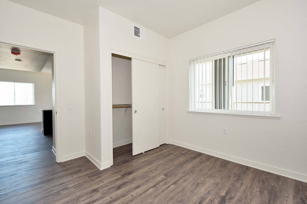 a bedroom with hardwood floors and white walls