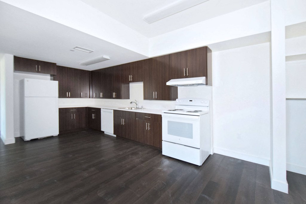 an empty kitchen with white appliances and wood floors
