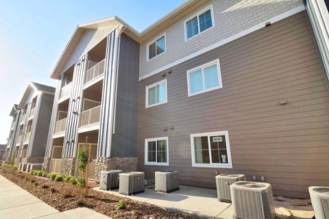 a large apartment building with a sidewalk and trash cans in front of it