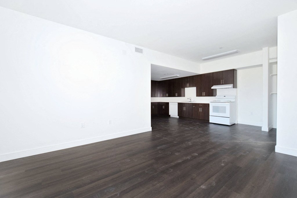 an empty living room and kitchen with white walls and wood floors