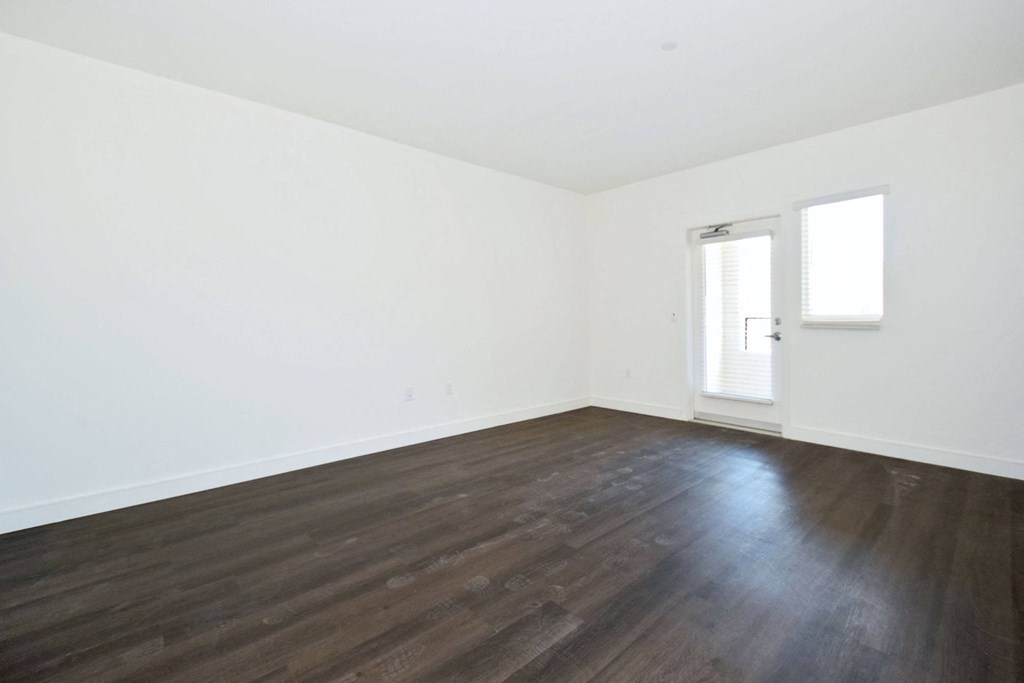 an empty room with white walls and wood floors