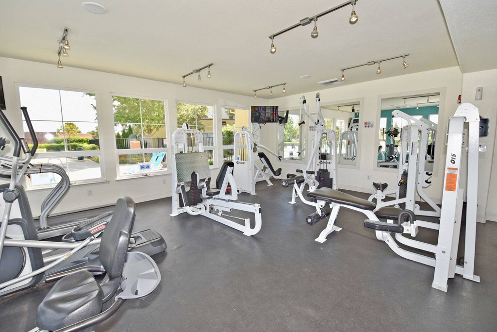 a gym with cardio equipment and weights on the floor