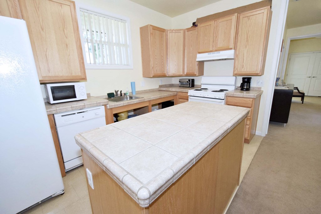 a kitchen with wooden cabinets and a white counter top