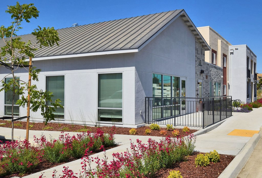 a building with a sidewalk and plants in front of it