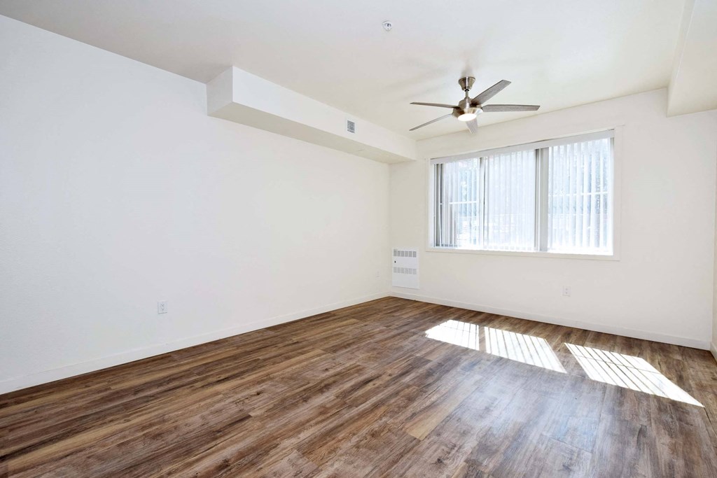 an empty living room with hard wood floors and a ceiling fan