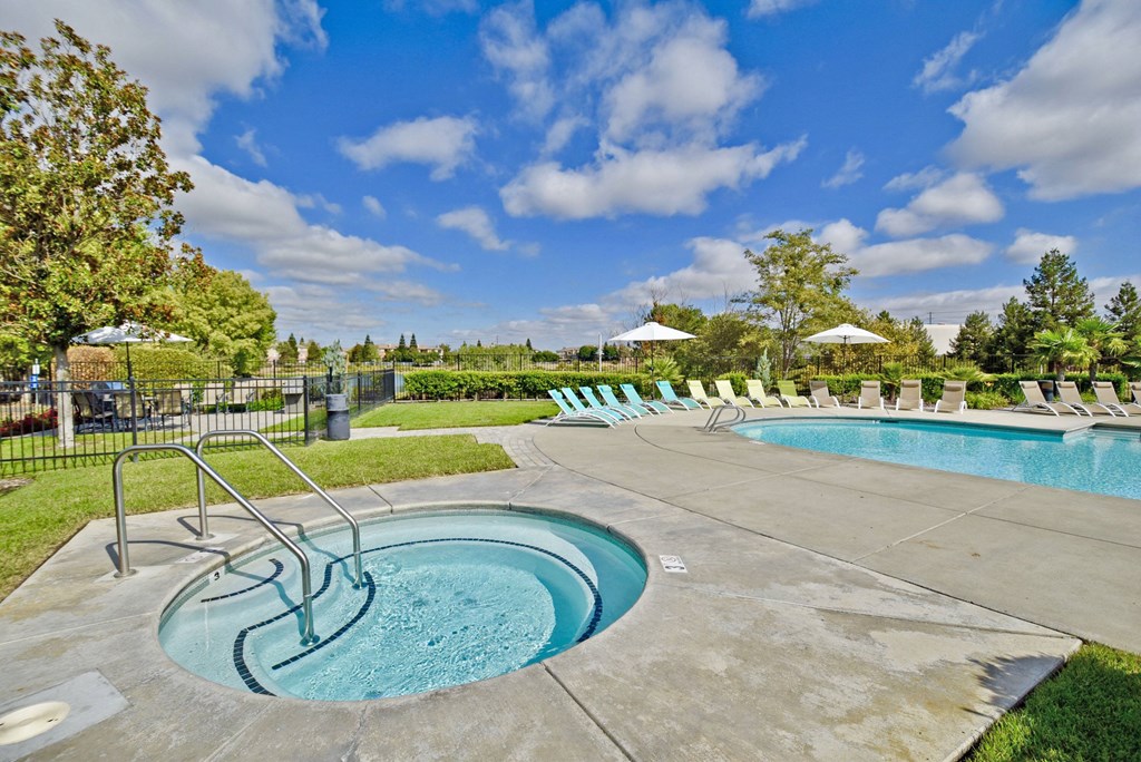 a resort style pool with chaise lounge chairs and a blue sky