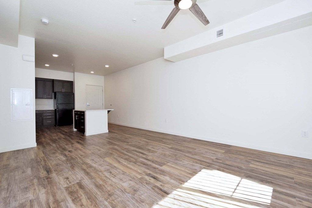an empty living room and kitchen with a ceiling fan