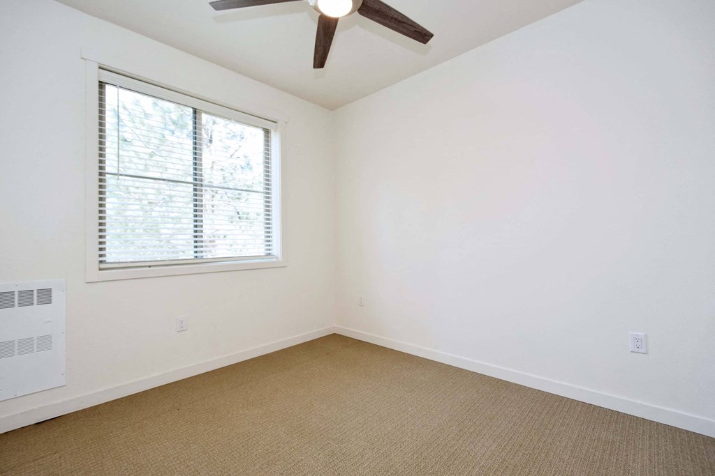 an empty room with a window and a ceiling fan
