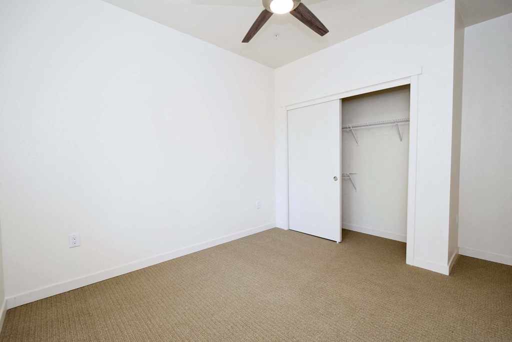a bedroom with a closet and a ceiling fan