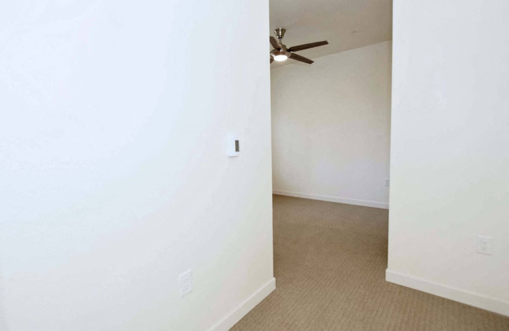 a bedroom with white walls and a ceiling fan