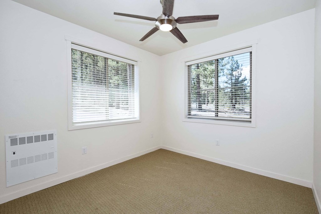 a living room with two windows and a ceiling fan