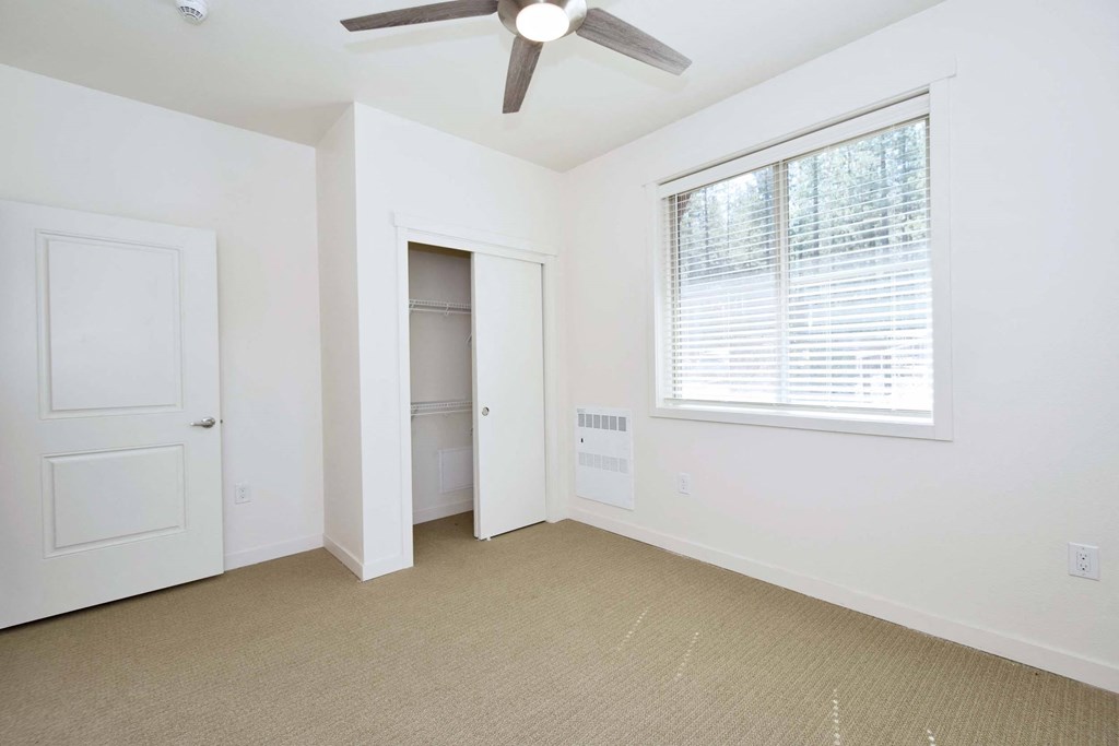 an empty bedroom with a ceiling fan and a closet