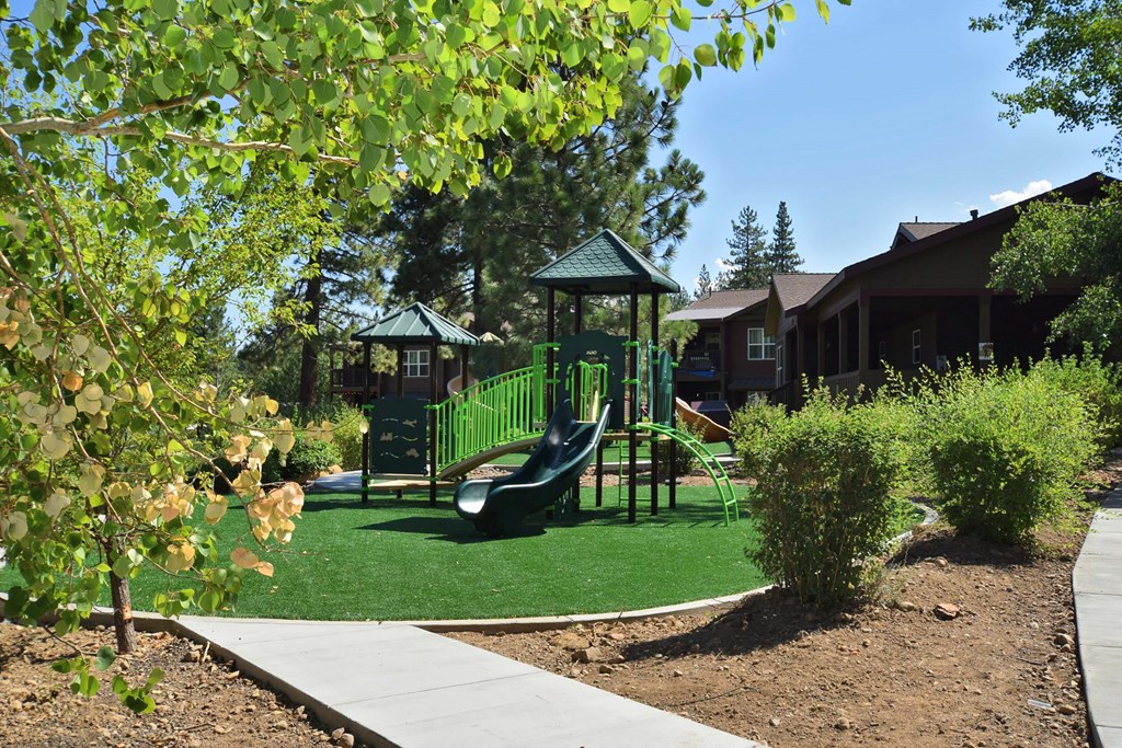 a playground with a swing set in front of a house