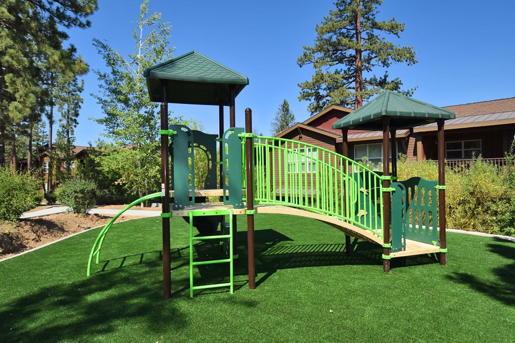 a playground with a slide and a play set in front of a house