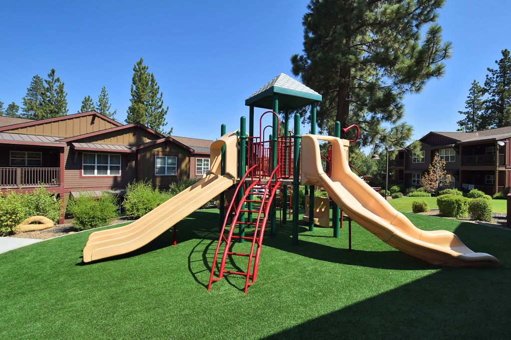 a playground with a set of slides in front of an apartment complex