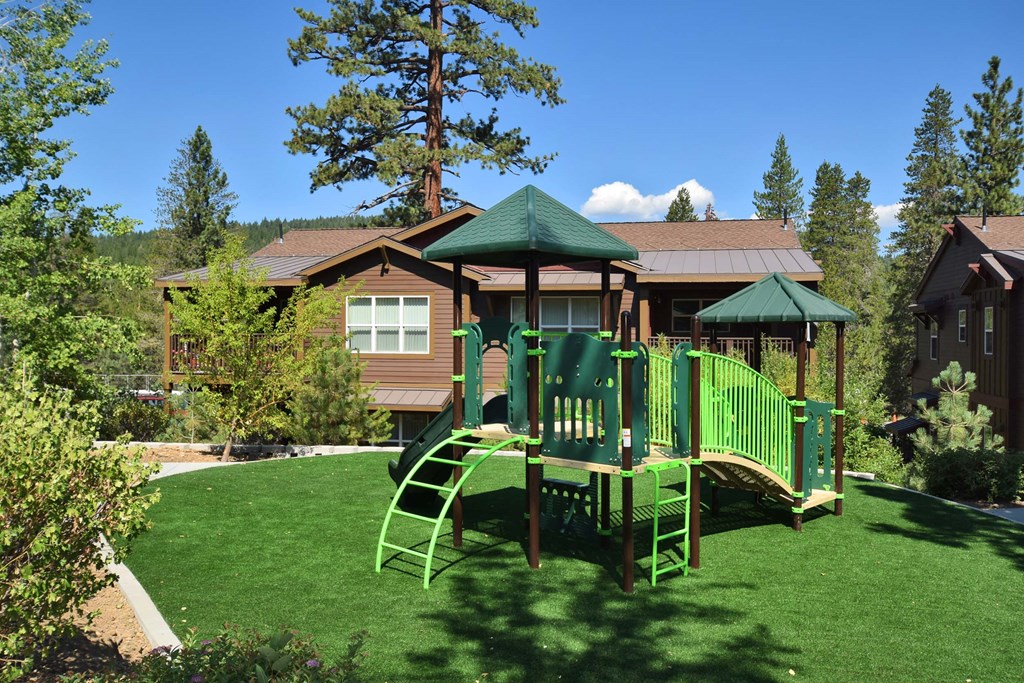a playground with a swing set in front of a house