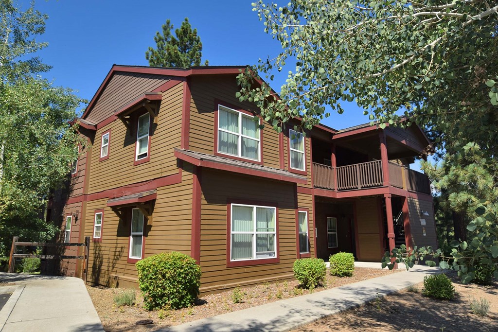 a red and brown house with a sidewalk and trees