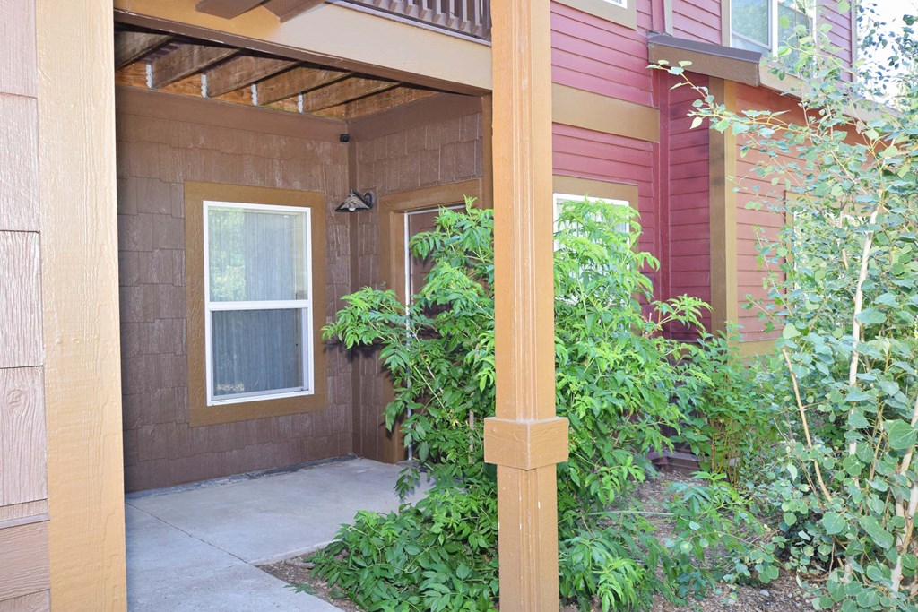 a covered porch in front of a house with plants