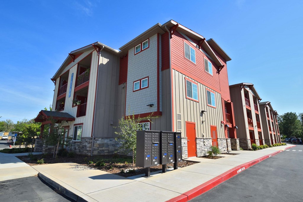a row of apartment buildings with red doors and gray and red siding