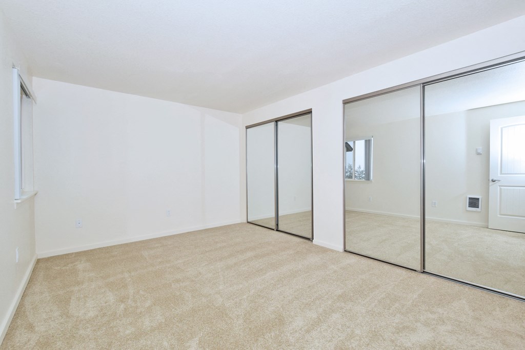 an empty living room with mirrors on the wall and carpeting