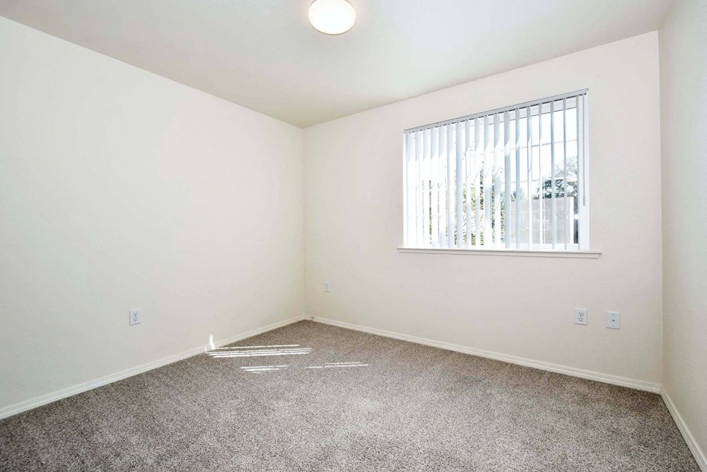 a bedroom with white walls and a window