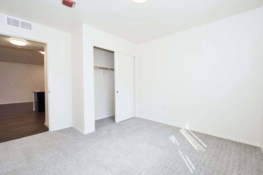 a bedroom with white walls and a door to a closet