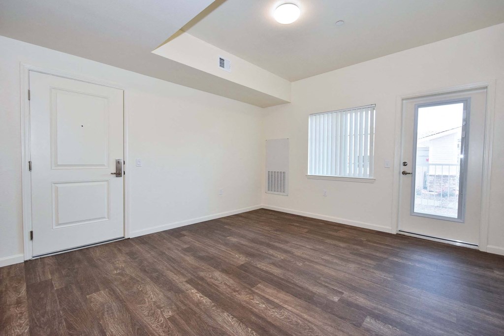 the living room of an empty home with wood flooring and white walls