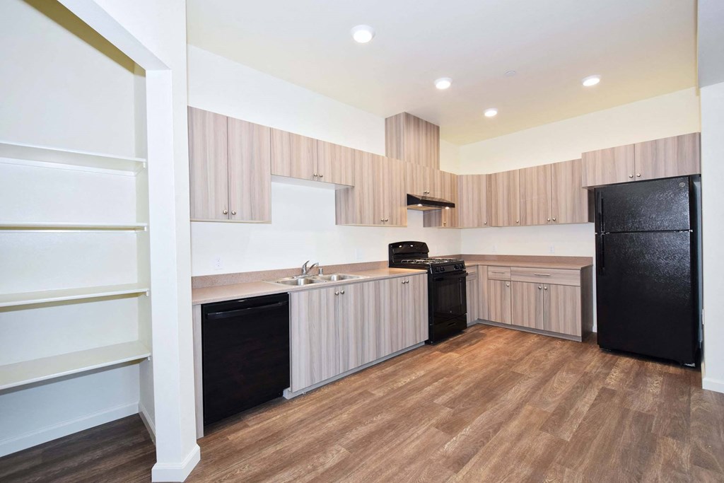 a kitchen with wood flooring and a black refrigerator